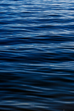 Vertical shot of deep blue sea water surface with gentle ripples.