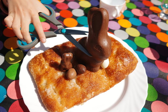 Child Cuts Chocolate Easter Bunny on Colorful Table