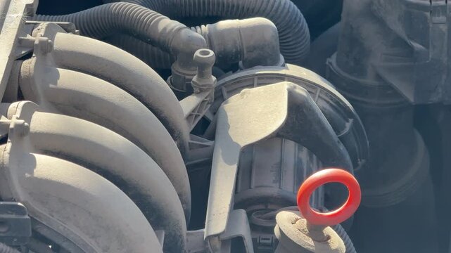 Dusty gasoline engine vibrates while running in an older car, close-up of intake manifold and oil dipstick, engine operation, repair and maintenance concept.