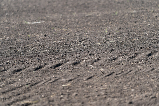 Close-up of dry cracked soil with small gravel and tire tracks