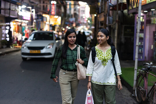 Two young woman walking through a street and interacting 