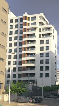 Vertical view of a modern residential apartment building with balconies, large windows and contemporary facade design. Urban housing architecture in Madrid, Spain, captured on a sunny day.