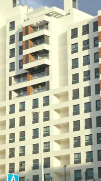 Vertical view of a modern high-rise residential apartment building with balconies, large windows and contemporary architecture. Urban housing and residential real estate in Madrid, Spain.