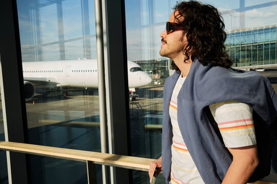 Man looking outside airport terminal windows before flight