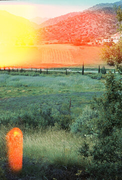 Sunset Over Fields and Hills Near a Small Village in Summer