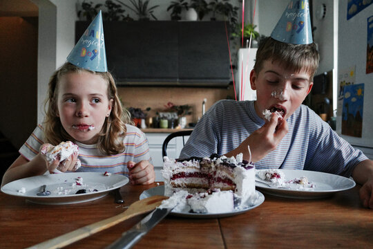 Children eating messy birthday cake celebrating party