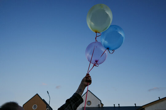 Hand holding colorful balloons skyward celebrating freedom hope