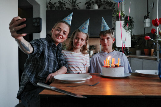 Family celebrating birthday with cake and selfie