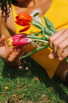 Holding a bouquet of flowers in a green field on a sunny day