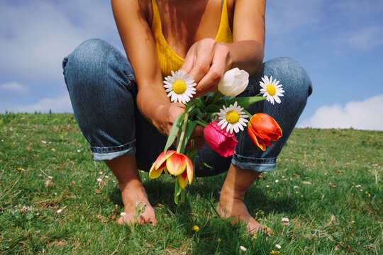 Person holds a colorful flower bouquet on a grassy hill