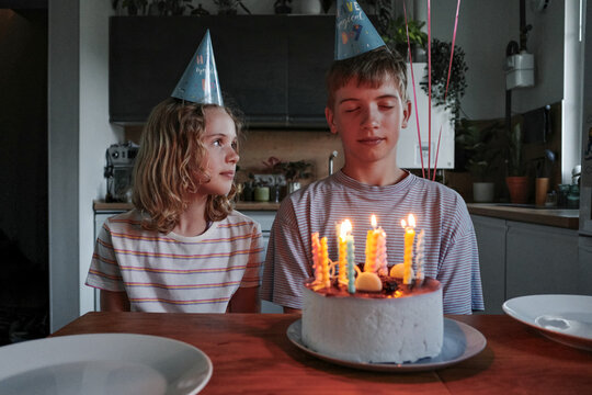 Siblings celebrating birthday party with cake and candles