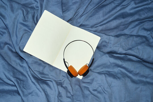 Notebook with headphones on blue bedding