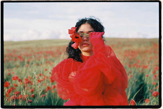 Woman holding poppy flowers covering eyes 