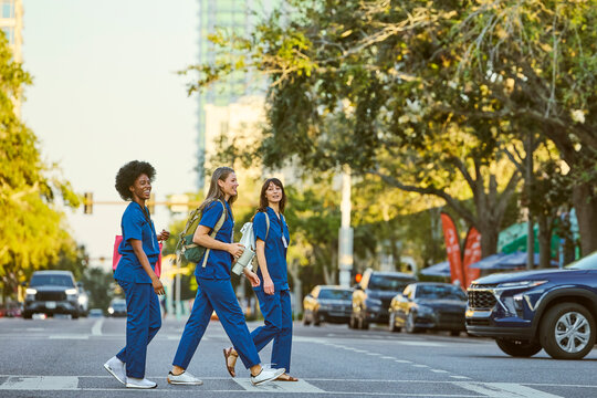 Three Nurses Walk on a City Street During Sunset