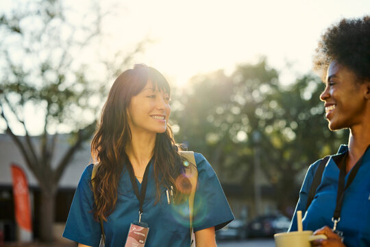 Two Healthcare Workers Talk Outside on a Sunny Day