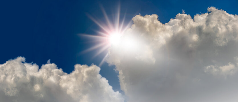 Bright sun rays emerging from cumulus clouds in blue sky, Bright sunlight shining through towering white clouds against a deep blue sky. Dramatic cloudscape with sunburst effect, symbolizing hope