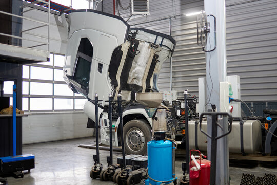 This image features an oil change machine strategically placed near a truck with a white cab in an active car service area, illustrating essential automotive repair tools and facilities.