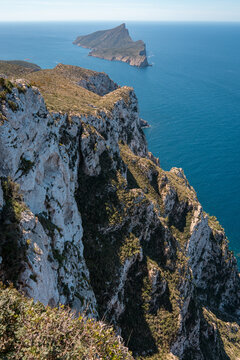 View of the rugged cliffs of Mallorca overlooking the Mediterranean Sea with Sa Dragonera island in the distance under a clear sky in Andratx, Balearic Islands, Spain.