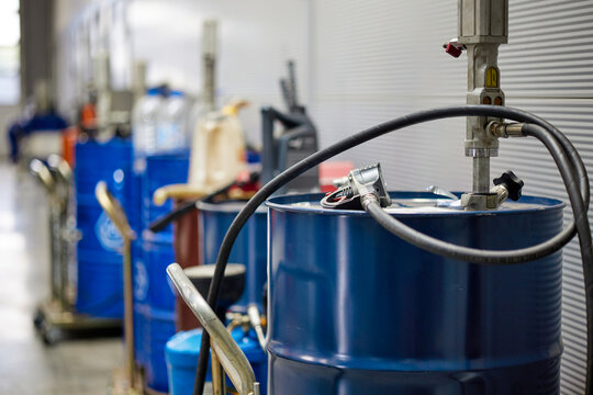 A professional car service garage featuring a neat row of blue oil barrels. The barrels are organized and ready for use, reflecting a clean and efficient automotive environment.