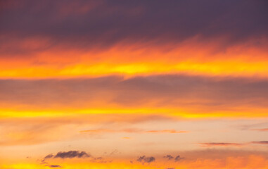 Fototapeta premium Dramatic sunset sky filled with vibrant orange and yellow burning clouds during twilight golden hour