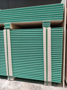 Blue gypsum plasterboards neatly arranged in rows within a construction warehouse