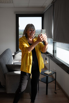 Happy older woman taking a selfless at home