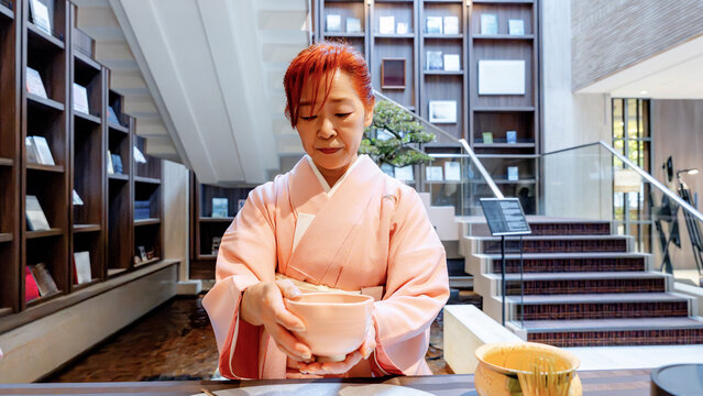 Japanese woman preparing matcha tea in serene interior