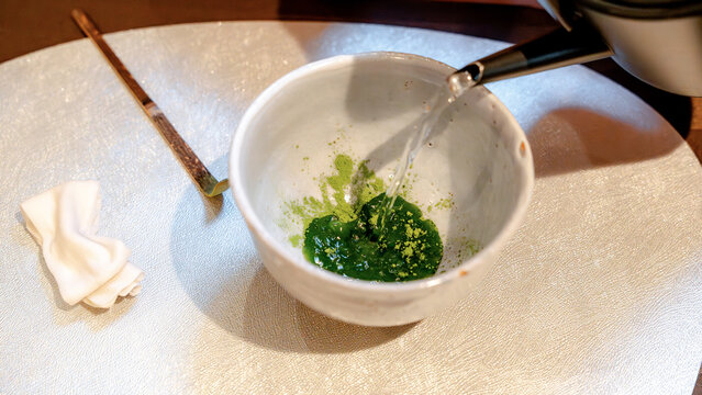 Matcha tea preparation with hot water poured into bowl