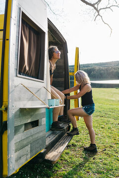 Two women climbing into camper van on lakeside holiday