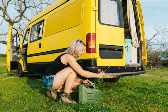 Woman refueling camper van during rural holiday trip