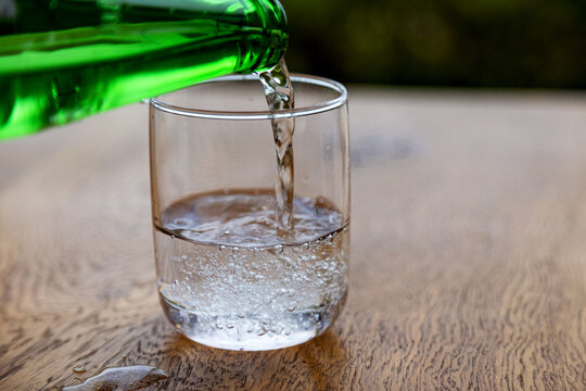 Pouring sparkling water from green bottle into glass