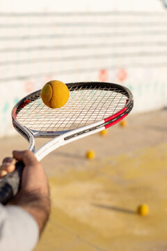 Tennis racket closeup with ball on strings at practice