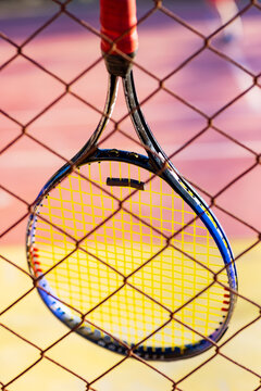 Tennis racket close-up hanging on fence at sunset court