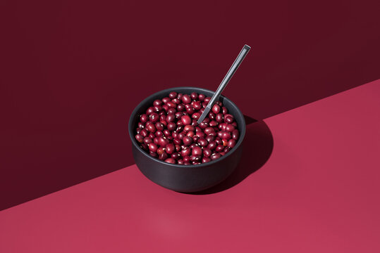 Red beans in bowl with spoon on a dark red background