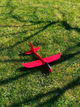Red foam glider toy plane resting on green grass lawn