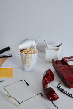 Vintage red phone and instant noodles on white office desk