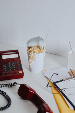 Vintage red phone and noodles on white office desk