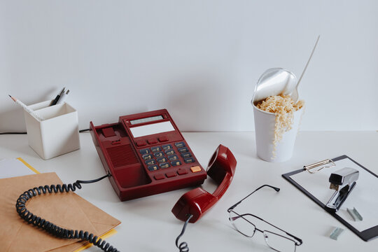 Vintage red phone with noodles on white office desk