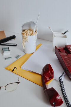 Vintage red phone and noodles on white office desk