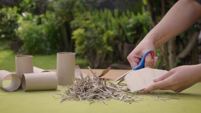 Woman cutting toilet paper tube into strips for composting in the garden