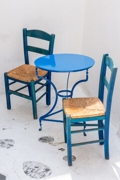 Blue bistro table with two rustic chairs in white corner