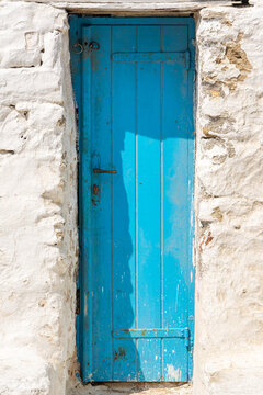 Weathered blue wooden door on white plaster stone wall