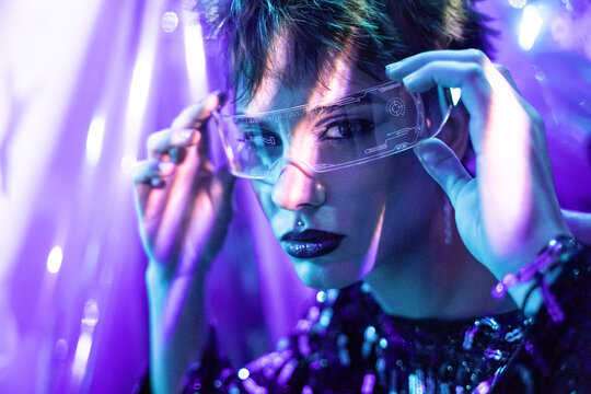 Cyberpunk young woman adjusting virtual reality visor