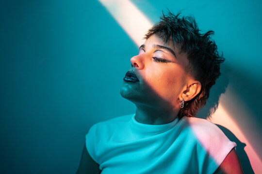 Young woman with dramatic makeup in teal light portrait