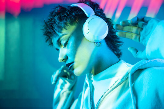 Young woman in headphones enjoying neon light music mood