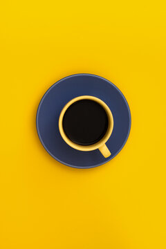 Black coffee cup on blue saucer over yellow background