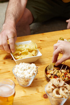 Hands sharing snacks and tapas at a wooden table