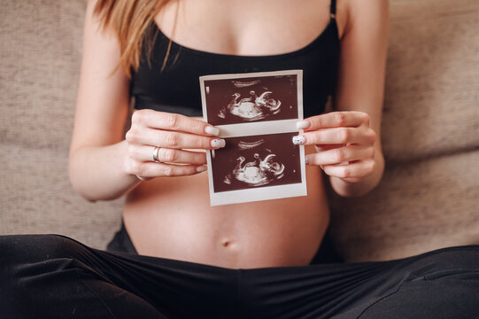 Pregnant woman holding ultrasound images of baby