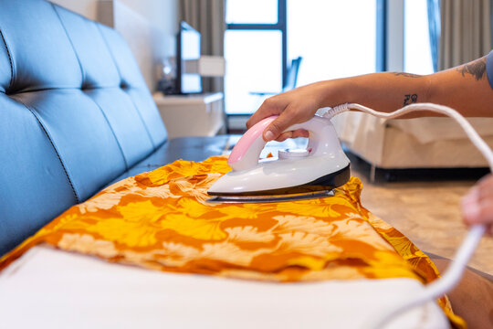 Person ironing clothes on couch as part of daily routine