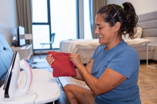 Woman ironing clothes at home as part of daily routine